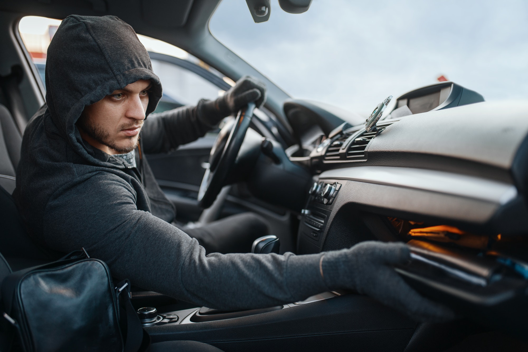 Car robber searches the glove compartment