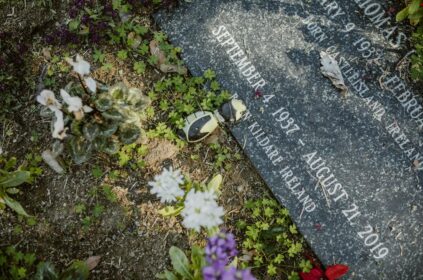 A gravestone adorned with flowers in a tranquil cemetery, symbolizing remembrance and peace.