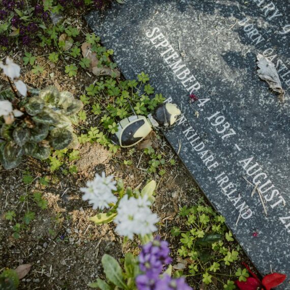 A gravestone adorned with flowers in a tranquil cemetery, symbolizing remembrance and peace.