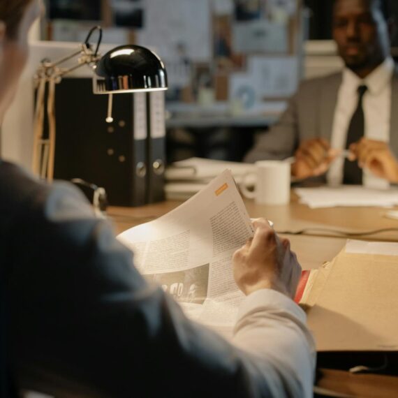 Two businessmen discuss strategies over documents in a well-lit office setting.