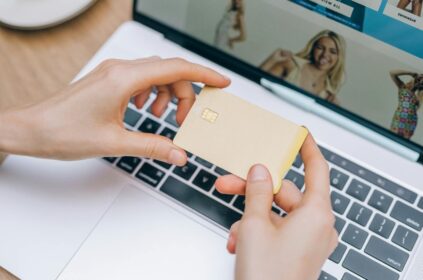 Close-up of hands holding credit card for online shopping on a laptop. Perfect for e-commerce and finance visuals.